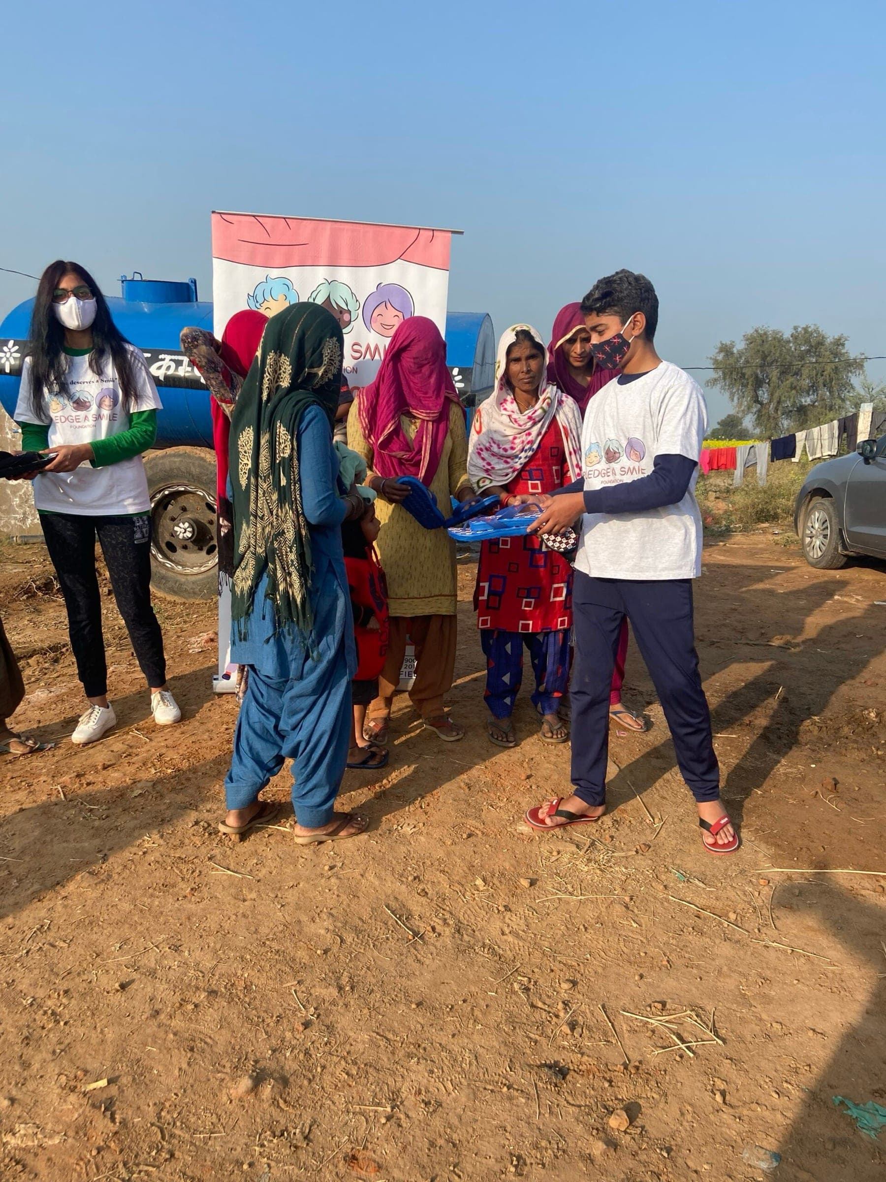 Teen volunteer distributing footwear to village women, golden light, real exchange