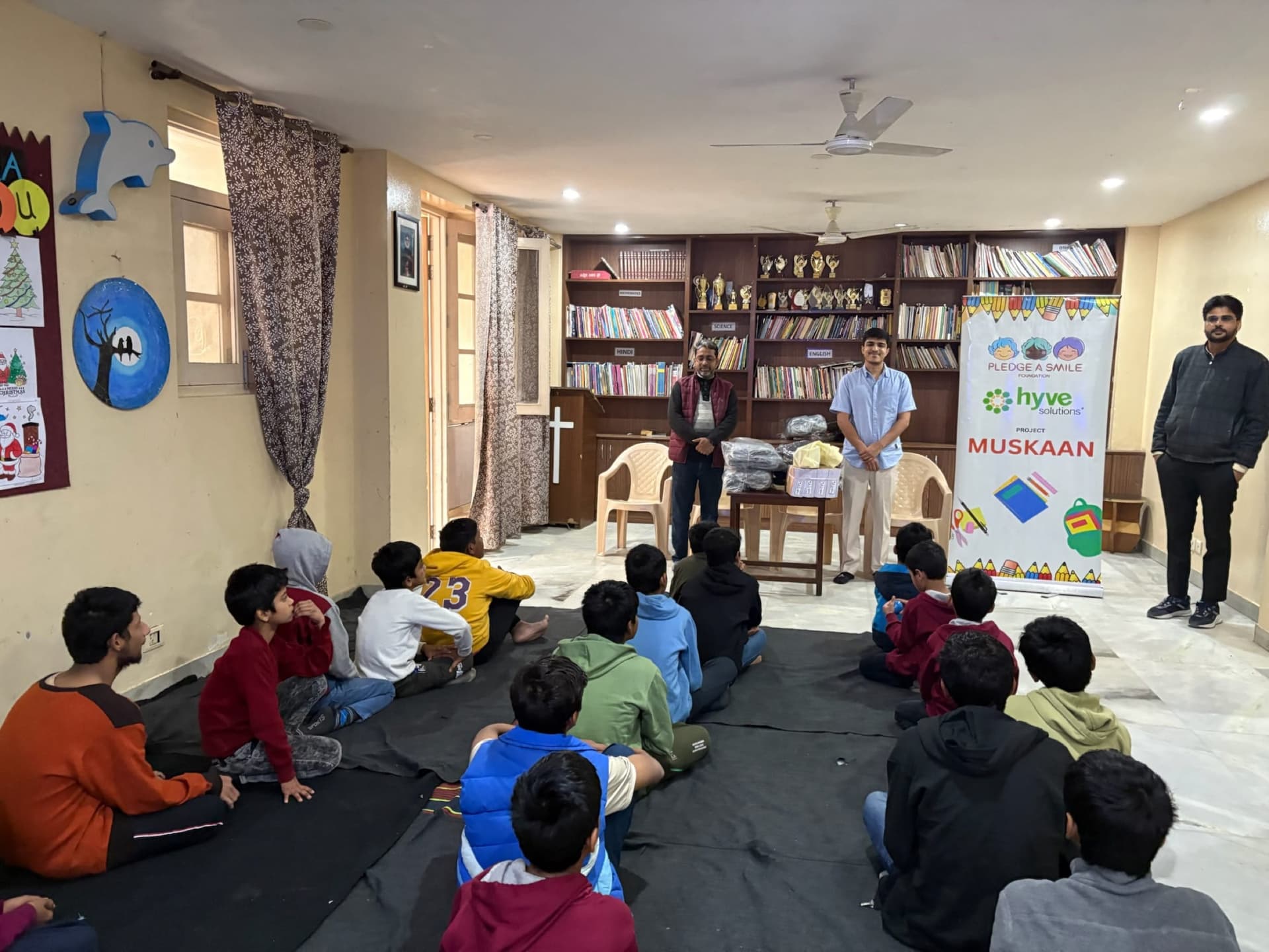 Boys seated on floor at shelter home during distribution briefing - quieter candid