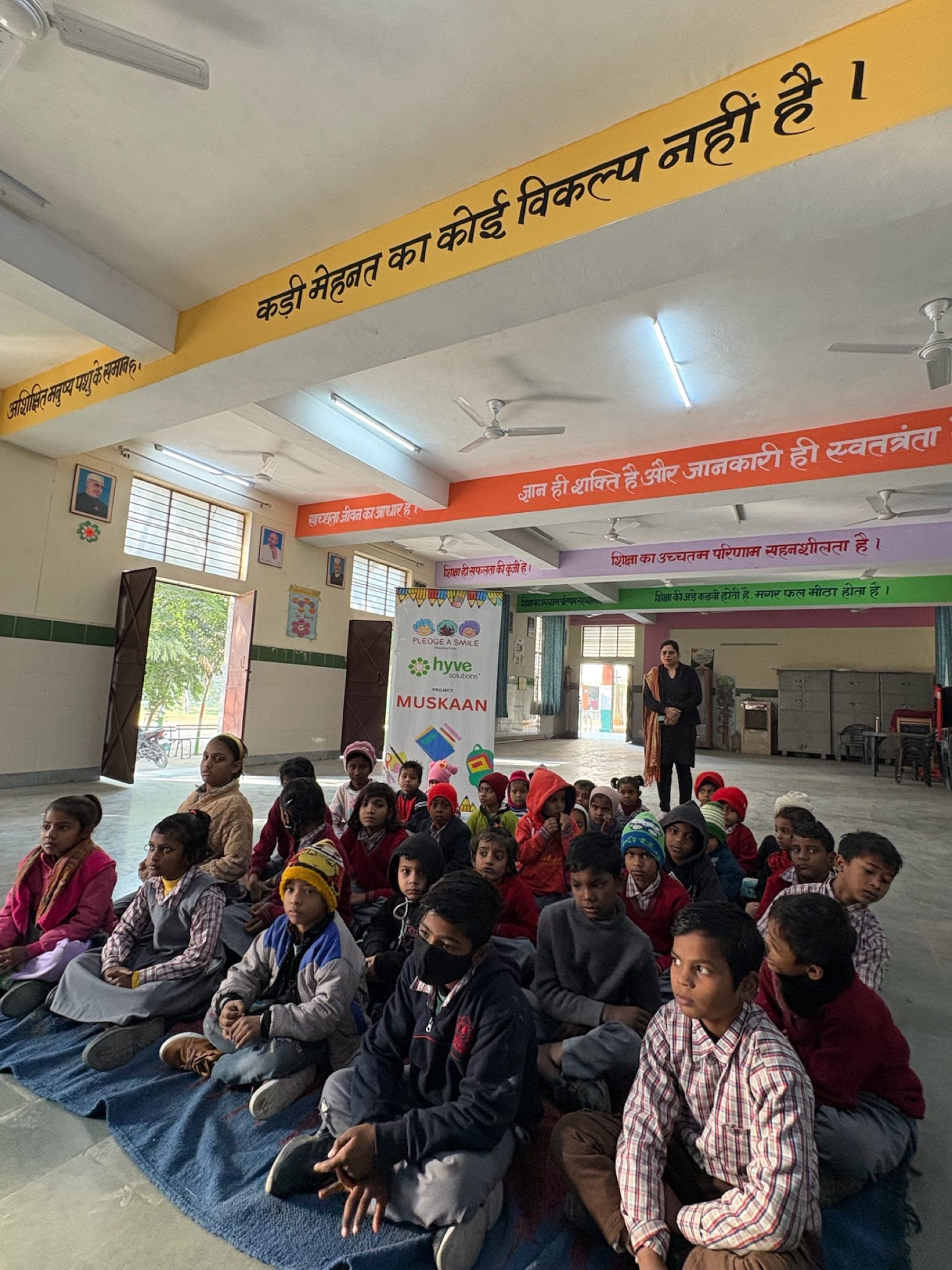 Children seated cross-legged indoors listening during winter session - candid audience