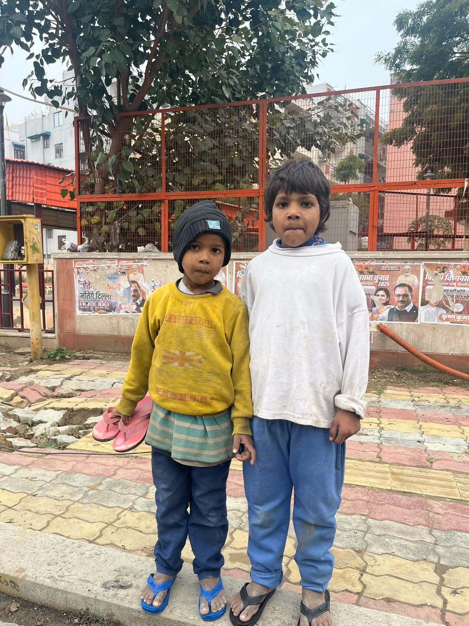 Two boys in winter sweaters stand together in a street portrait