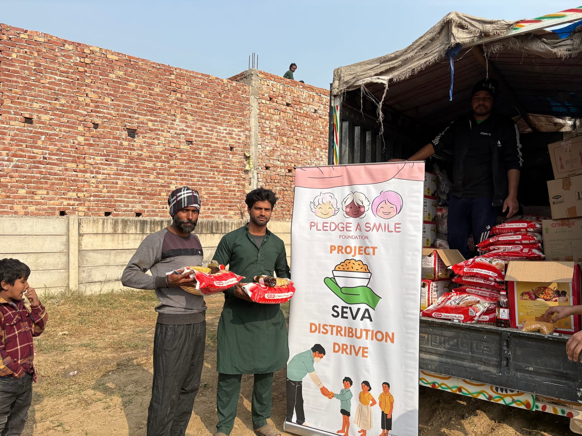 Two young men take ration packets as a man in the truck bed hands more down, a boy watching.