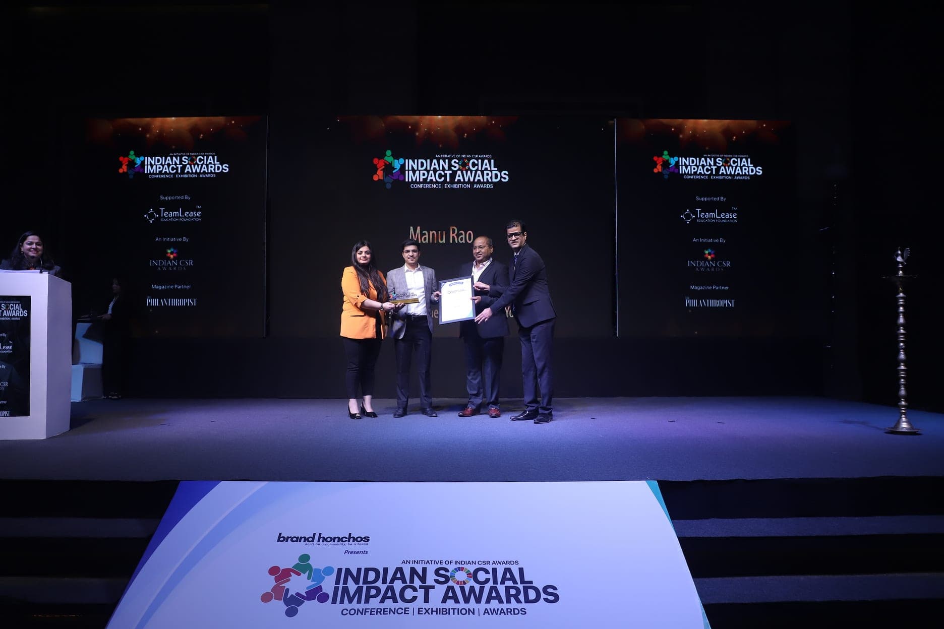 Manu Rao receiving the Best Individual Social Welfare Contributor (Youth) award on the Indian Social Impact Awards stage, name on screen