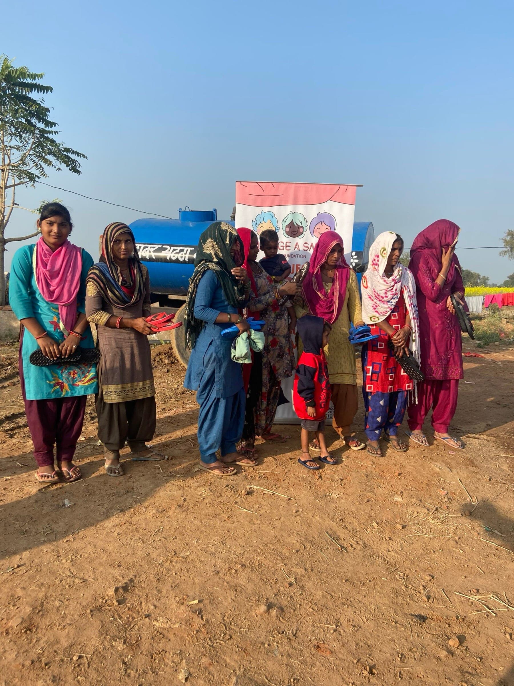 A row of women holding new footwear in colourful dupattas in warm morning light
