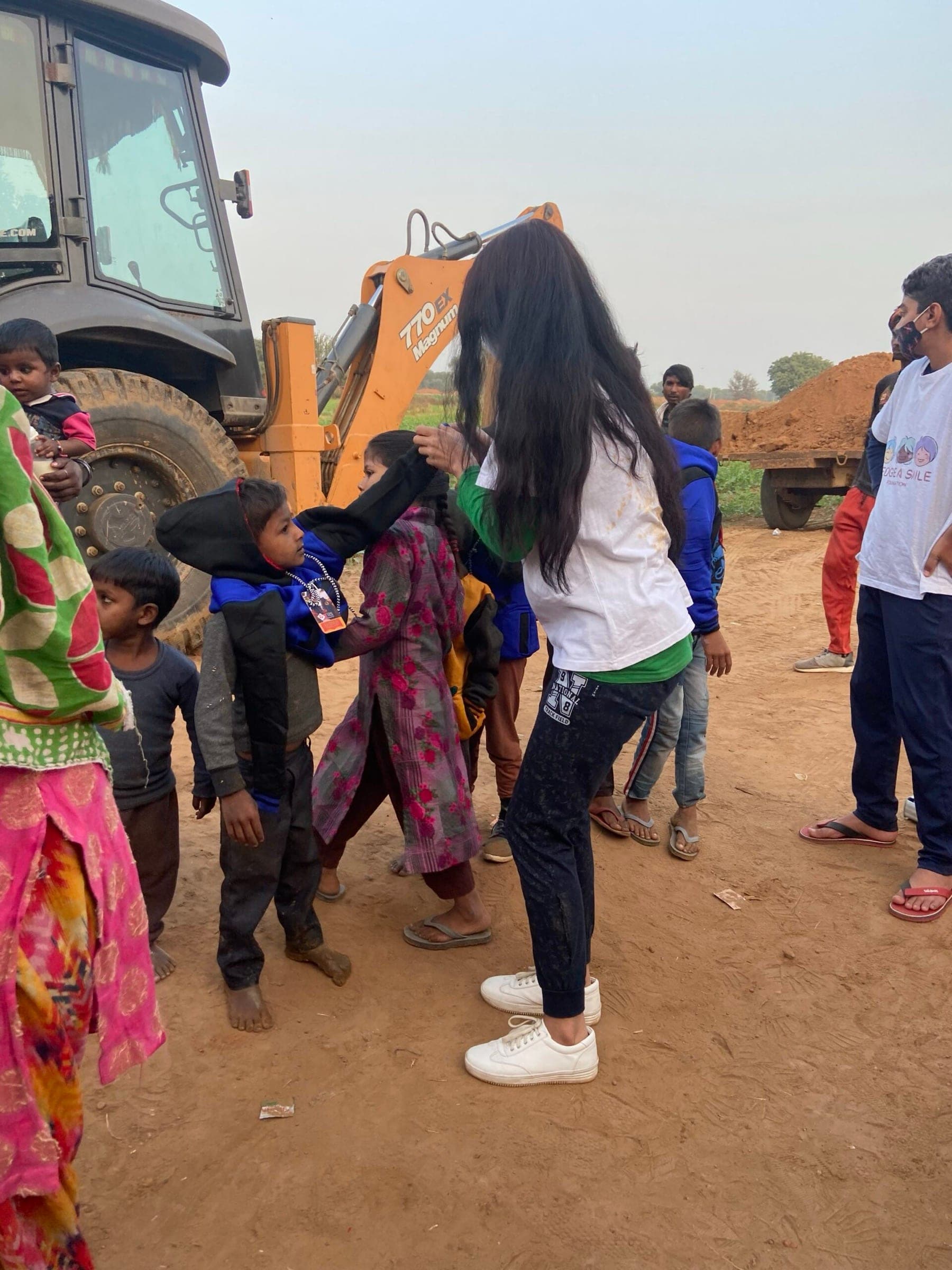 A volunteer helping a small child pull on a new hoodie