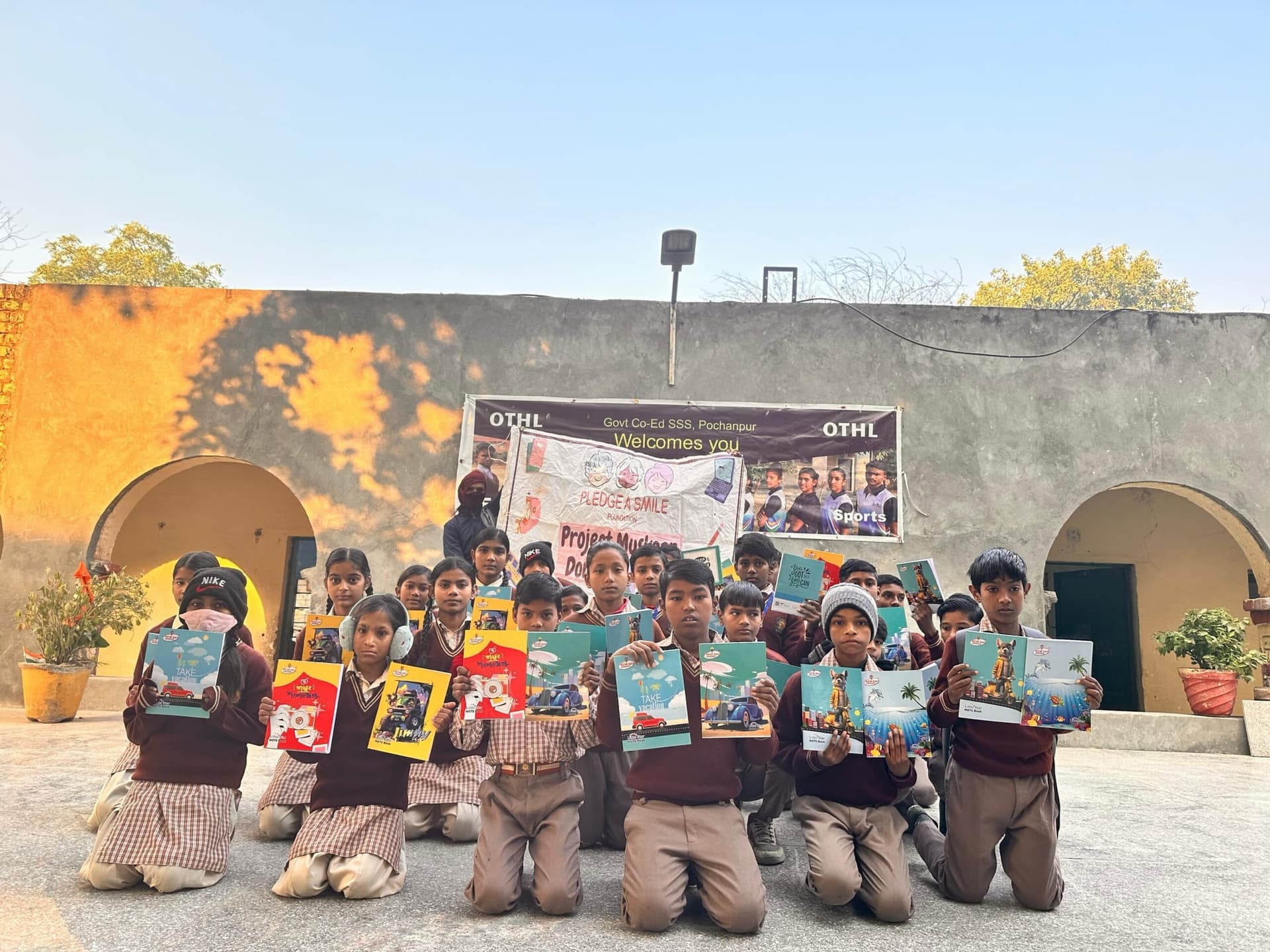 Children hold up new notebooks in golden courtyard light