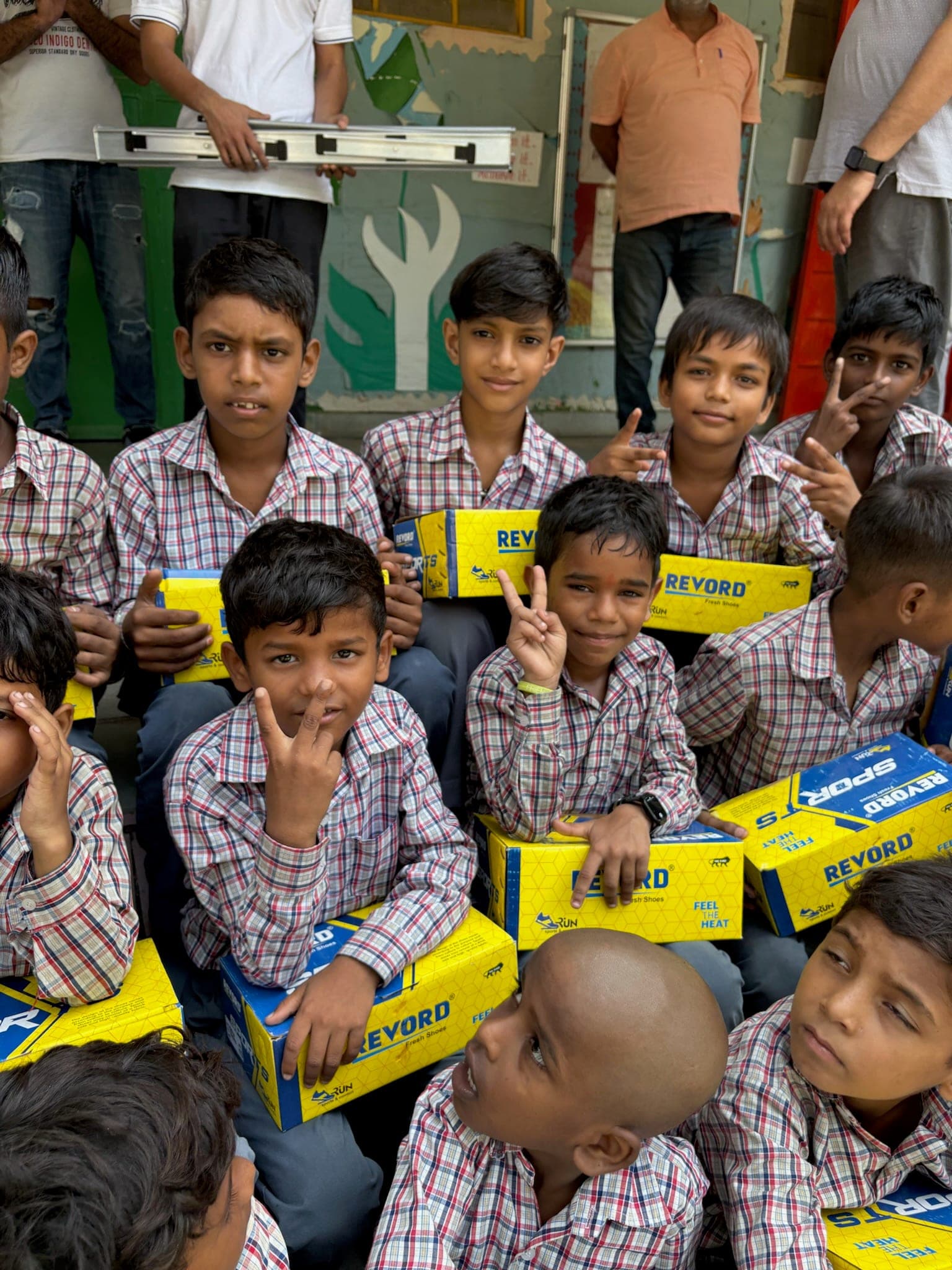Boys hold up their new shoe boxes with peace signs and unfiltered joy at a Pochanpur shoe-distribution day.
