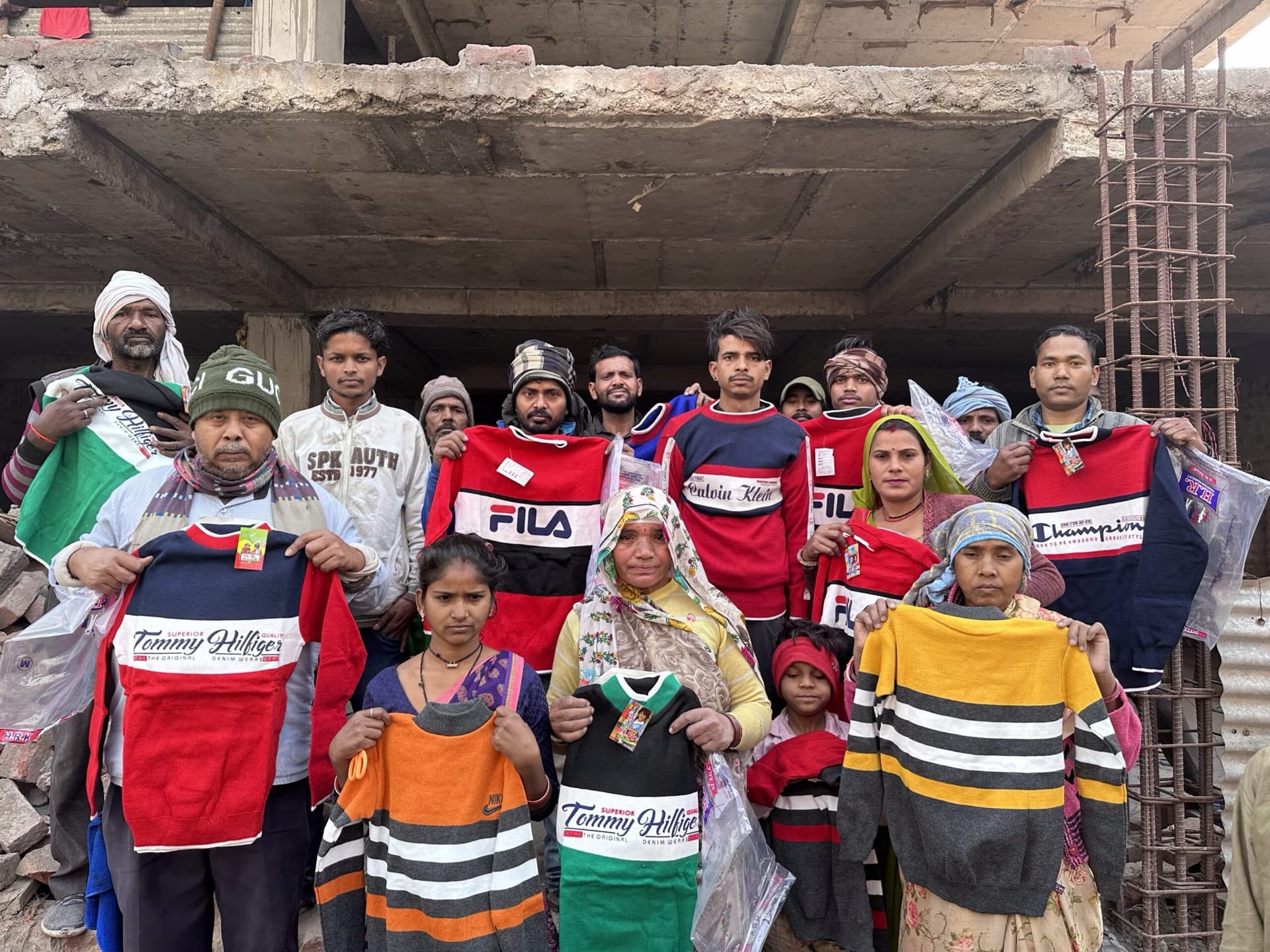 A community at an under-construction building holds up newly received blankets