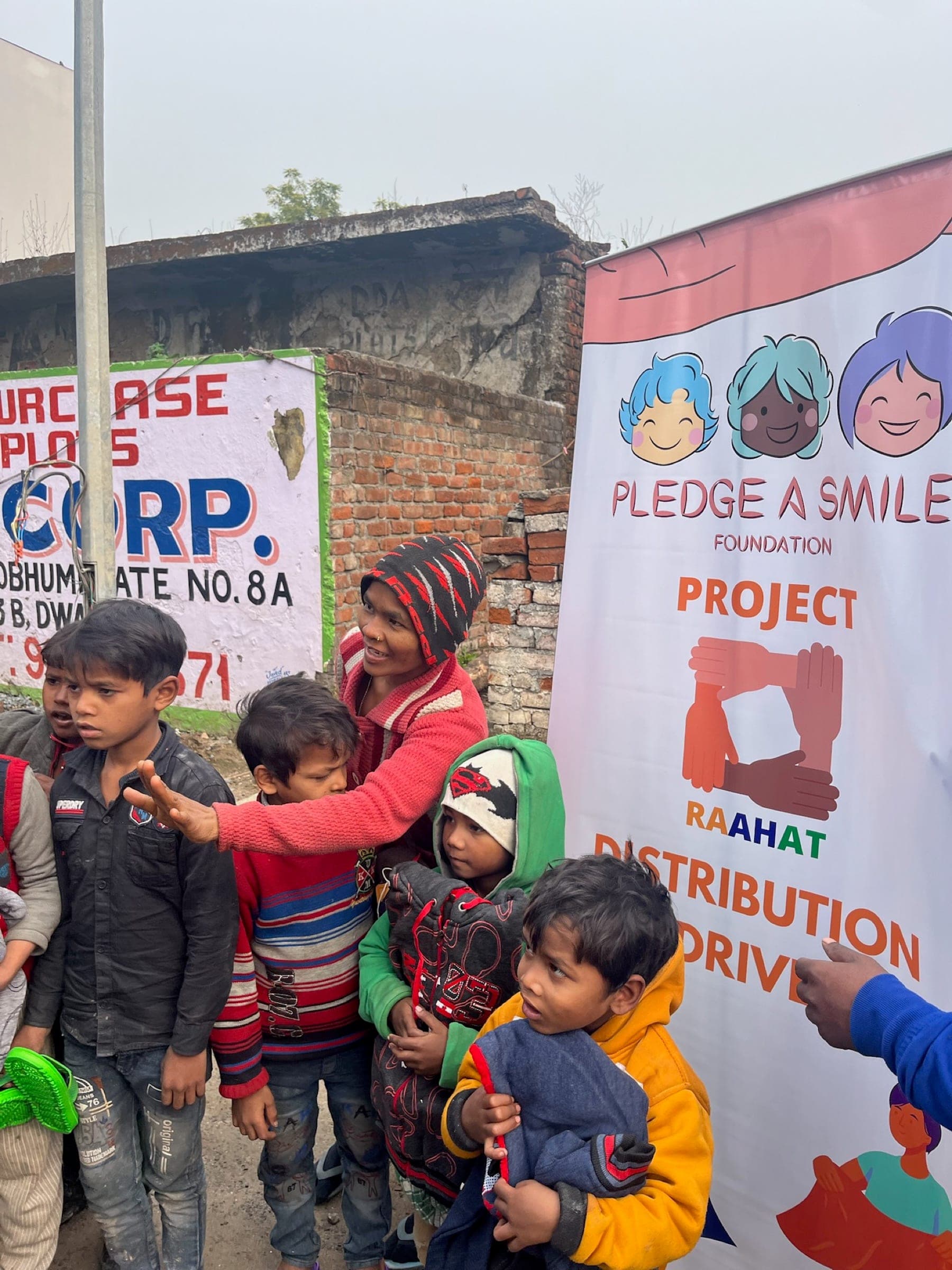 Candid: mother reaching across a cluster of bundled-up kids beside the banner