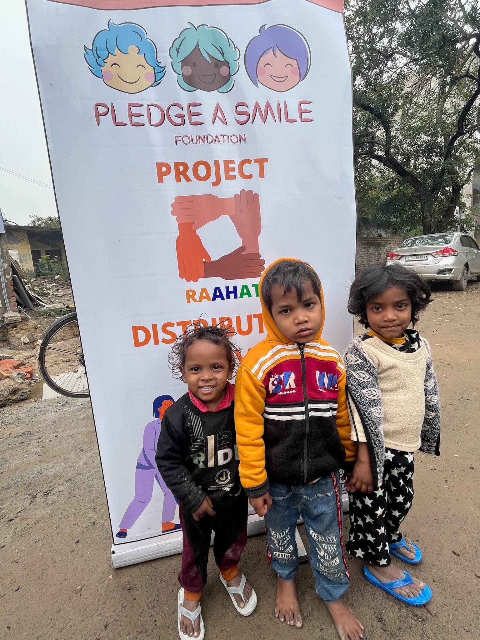 Three young siblings, closely cropped, break into genuine joyful smiles at the Raahat banner.