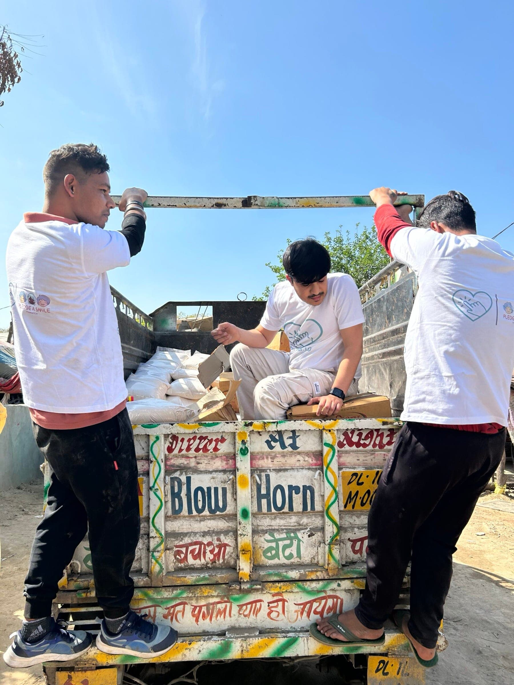 Volunteers climbing onto a painted truck to unload ration sacks at the start of a drive