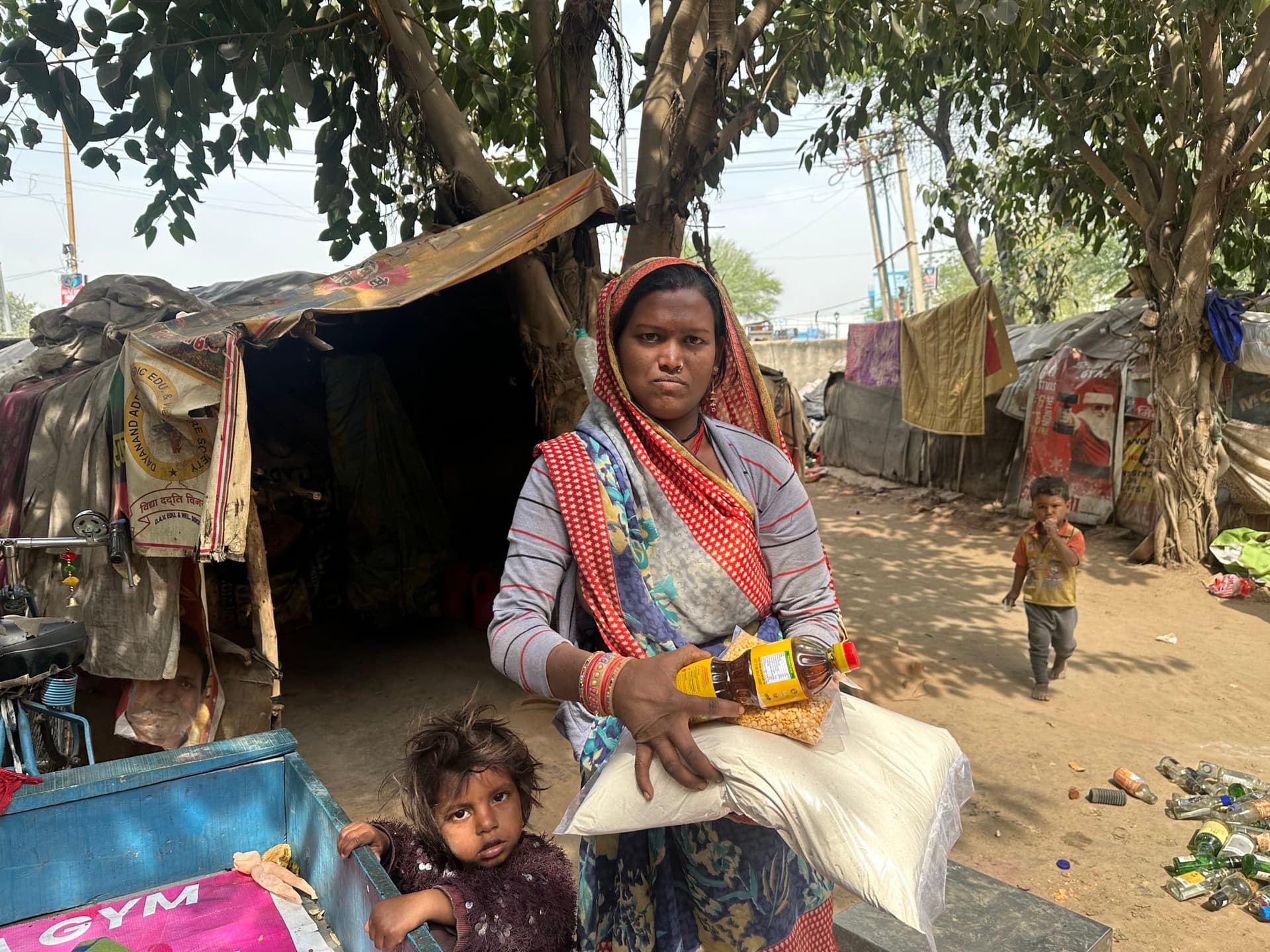 A mother sits at home with her two children and their Seva ration kit