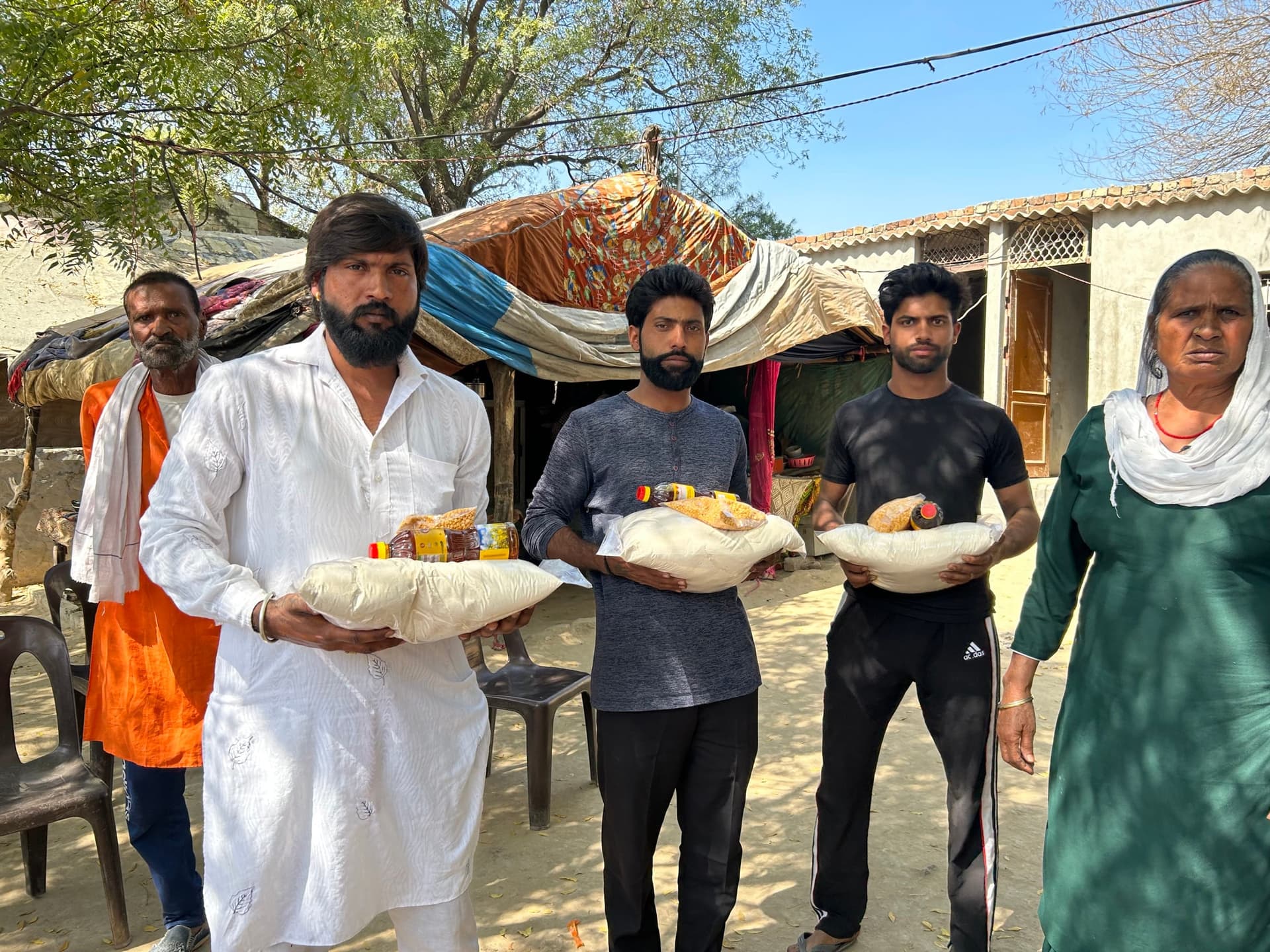 Family holding dry ration kits (rice, oil, dal)